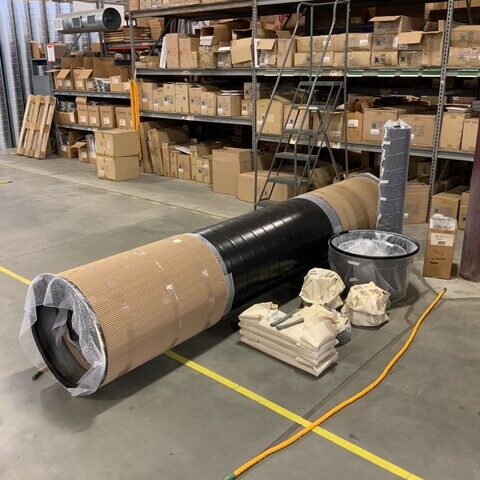 Wrapped ductwork materials stored in a warehouse with shelving
