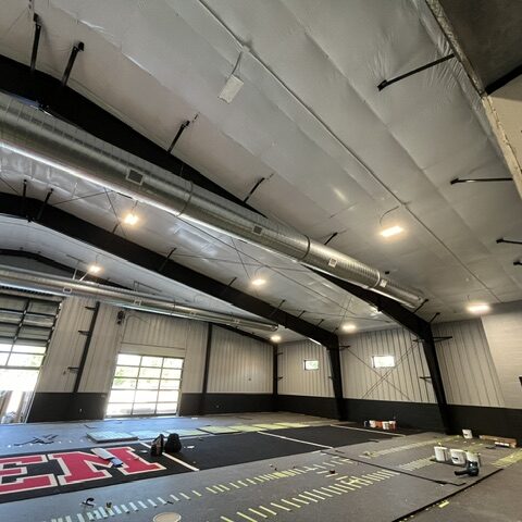 Long run of exposed spiral ductwork with registers in an indoor training facility
