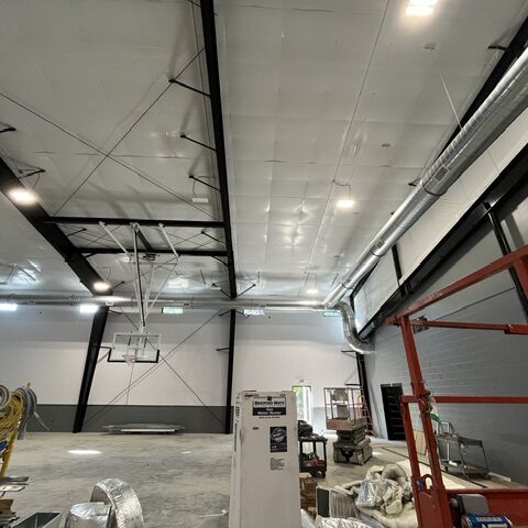 Large round spiral ductwork installed along the wall and ceiling of a commercial gym