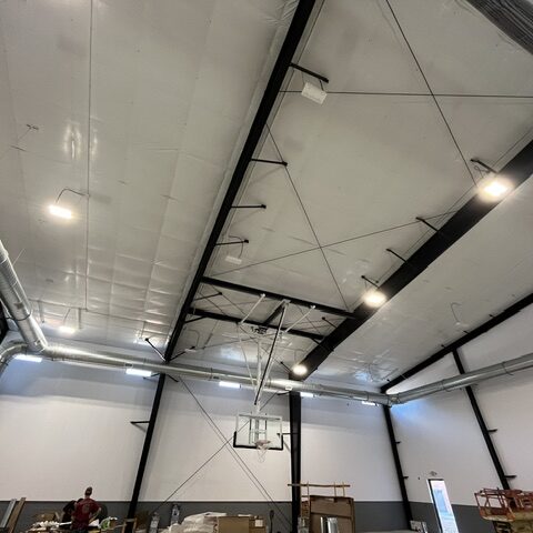 Spiral HVAC ductwork running along the ceiling and wall of an indoor gym facility